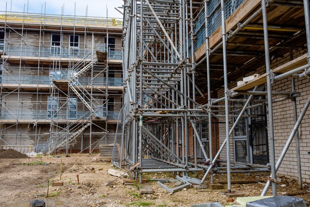 Gerüst und provisorische Zugangstreppe auf Neubau-Baustelle rund um neues mehrstöckiges Haus, um Verkleidungen, Fenster und Dachmontage zu ermöglichen