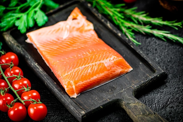 Gesalzener Lachs mit Gemüse und Tomaten auf einem Schneidebrett