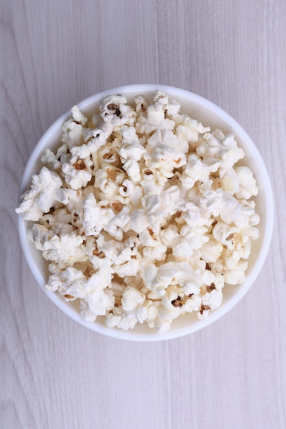 Gesalzenes Popcorn in einer Schüssel auf einem Holztisch. Draufsicht