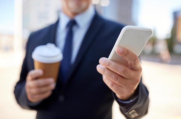 Geschäft, Heißgetränke, Pause und Menschen und Konzept - Senior-Geschäftsmann mit Smartphone trinkt Kaffee aus Einweg-Pappbecher im Freien