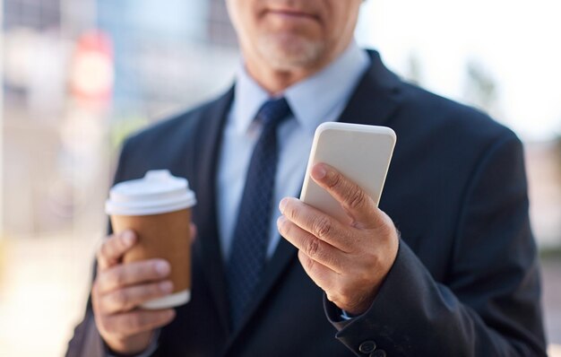 Foto geschäft, heißgetränke, pause und menschen und konzept - senior-geschäftsmann mit smartphone trinkt kaffee aus einweg-pappbecher im freien