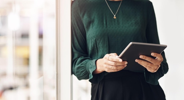 Geschäft in der Welt der Technologie Abgeschnittenes Porträt einer nicht erkennbaren jungen Geschäftsfrau, die ihr Tablet benutzt, während sie im Büro steht