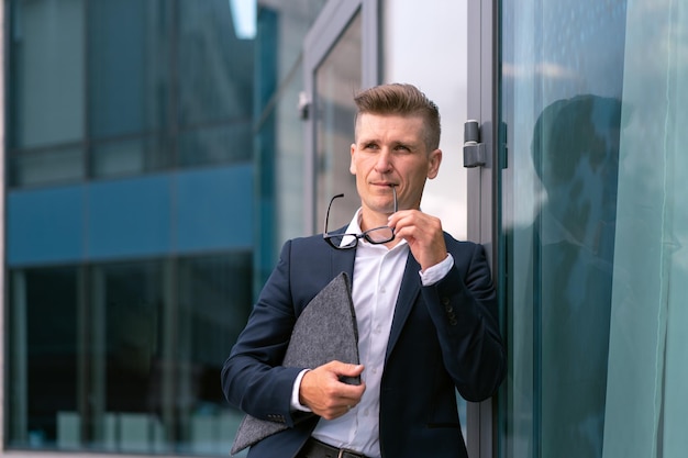 Geschäft Kaufmann Brille mit Ordner stehend Bürogebäude Eingang gut aussehend kaukasischen männlichen Business Person Porträt Stadt korporative Gebäude Hintergrund erfolgreicher junger Erwachsener Manager