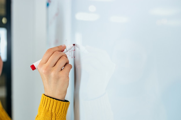 Geschäft, Leute, Ideen und Bildungskonzept. Weibliche Person, die auf whiteboard schreibt.