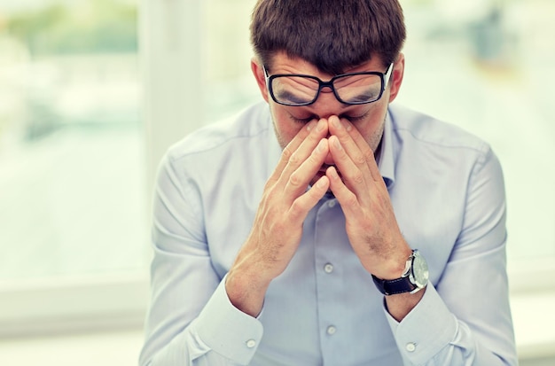 Geschäft, Menschen und Arbeitskonzept - müder Geschäftsmann mit Brille im Büro