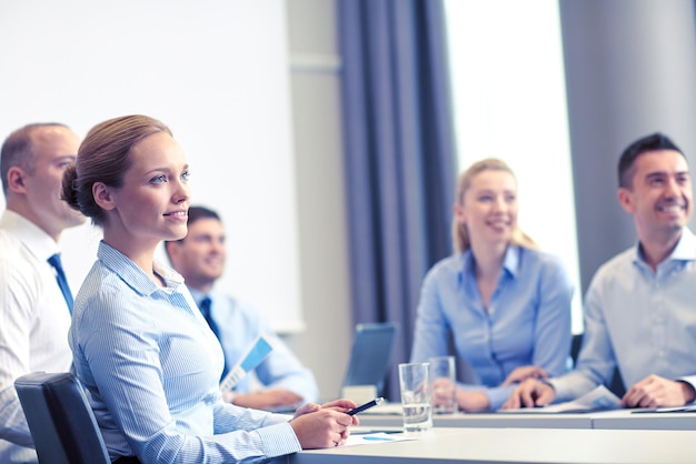 Geschäft, Menschen und Teamwork-Konzept - Gruppe lächelnder Geschäftsleute, die sich zur Präsentation im Büro treffen