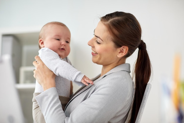 Geschäft, Mutterschaft, Multitasking, Familie und Menschenkonzept - glückliche lächelnde Geschäftsfrau mit Baby im Büro