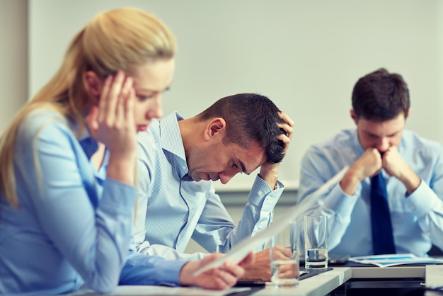 Foto geschäft, teamarbeit, menschen und krisenkonzept - geschäftsteam sitzt traurig und löst probleme im büro