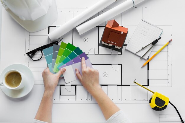 Geschäfts-, Architektur-, Gebäude-, Konstruktions- und Personenkonzept - Nahaufnahme von Designerhänden mit Farbpalette und Hausplan