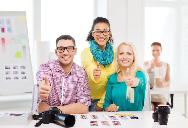 geschäfts-, bildungs-, fotografie-, büro- und startkonzept - lächelndes kreatives team mit gedruckten fotos, die im büro arbeiten