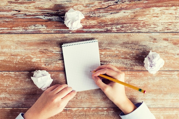 Foto geschäfts-, bildungs-, inspirations- und personenkonzept - nahaufnahme weiblicher hände mit notizbuch, bleistift und verkrampften papierbündeln auf dem tisch