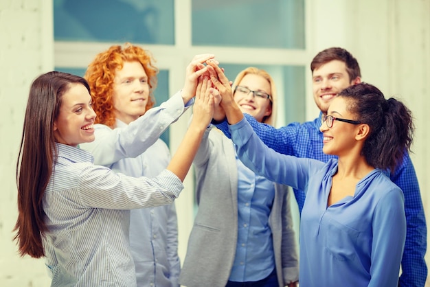 Geschäfts-, Büro-, Gesten- und Startup-Konzept - lächelndes Kreativteam, das im Büro eine High-Five-Geste macht