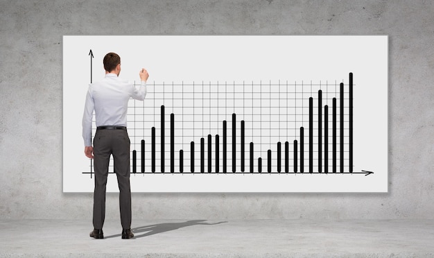 Geschäfts-, Entwicklungs- und Büromenschenkonzept - Geschäftsmann mit Markierungszeichnungsdiagramm über Betonmauerhintergrund von hinten