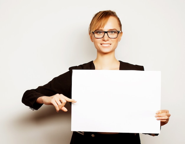 Geschäfts-, Finanz- und Leutekonzept: Porträt einer schönen Geschäftsfrau, die eine leere Anschlagtafel hält. Bereit, Text hinzuzufügen. Über grauem Hintergrund.