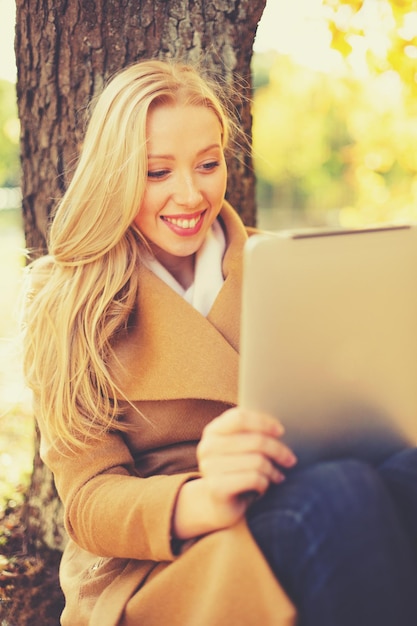 Geschäfts-, Kommunikations-, moderne Technologie- und Freizeitkonzept - Frau mit Tablet-PC im Herbstpark