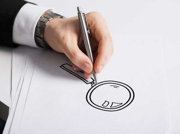Geschäfts-, Marketing-, Planungs- und Personenkonzept - Nahaufnahme der männlichen Hand mit Federzeichnungslinse auf weißem Papier