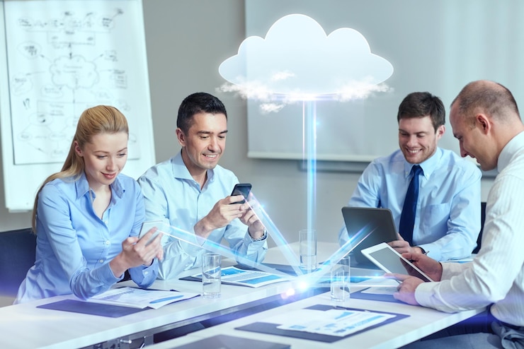 Foto geschäfts-, menschen-, cloud-computing- und technologiekonzept - lächelndes geschäftsteam mit smartphones, tablet-pc-computern, die im büro arbeiten