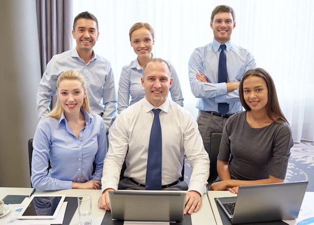 Geschäfts-, Menschen-, Technologie- und Teamwork-Konzept - lächelndes Geschäftsteam mit Laptop-Computern, die im Büro arbeiten