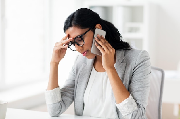 Geschäfts-, Menschen-, Termin- und Technologiekonzept - gestresste Geschäftsfrau ruft im Büro auf dem Smartphone an