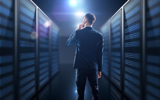 Geschäfts-, Menschen- und Technologiekonzept - Geschäftsmann im Anzug über Serverraumhintergrund