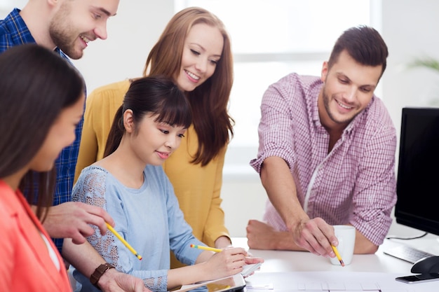 geschäfts-, start-, bildungs- und menschenkonzept - glückliches kreatives architektenteam oder studenten mit bauplänen, die im büro arbeiten