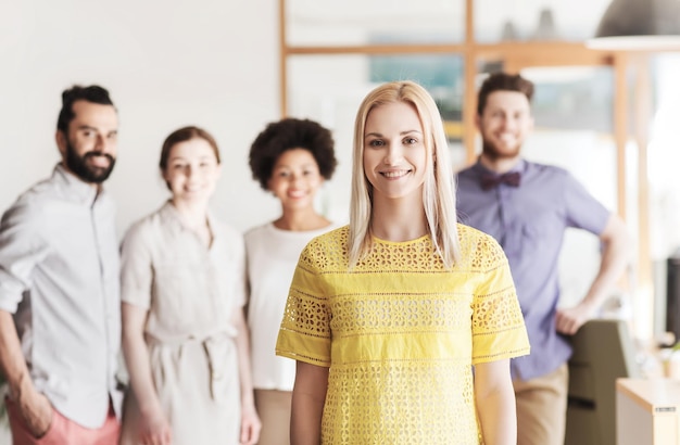 Foto geschäfts-, start-, personen- und teamwork-konzept - glückliche junge frau über kreativem team im büro