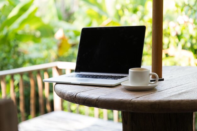 Geschäfts-, Technologie-, Getränke- und Objektkonzept - Kaffeetasse und Laptop-Computer auf dem Tisch im Freien