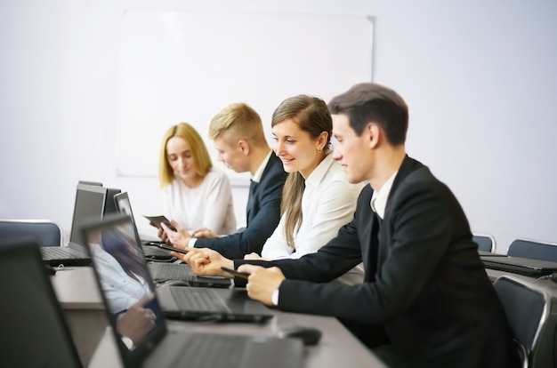 Geschäfts-, Technologie- und Bürokonzept - lächelndes Geschäftsteam mit Laptops und Dokumenten, die Diskussion im Büro haben