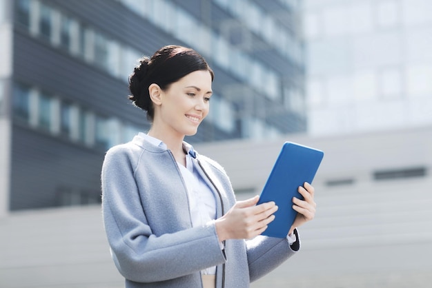 Geschäfts-, Technologie- und Personenkonzept - junge lächelnde Frau mit Tablet-PC-Computer über Bürogebäude