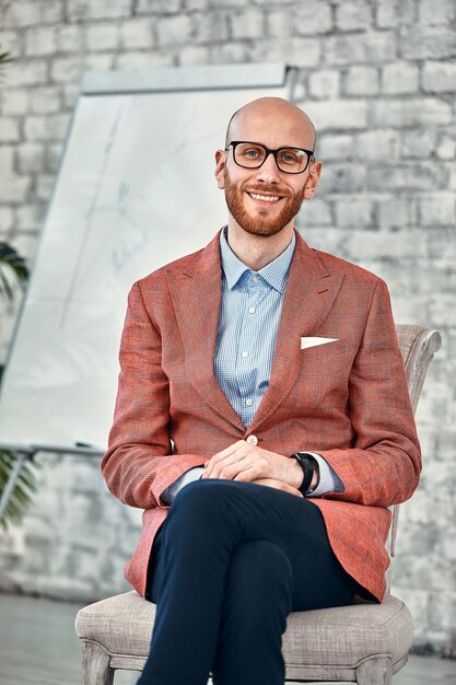 Geschäfts- und Bürokonzept - lächelnder hübscher Geschäftsmann sitzt auf chiar, Flip-Chat auf Oberfläche im Büro