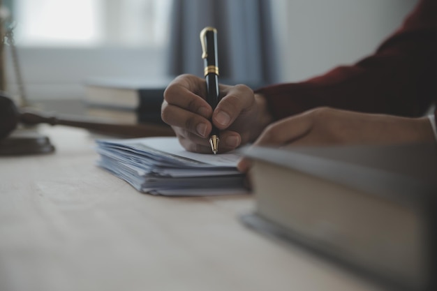 Geschäfts- und Rechtsanwälte diskutieren Vertragspapiere mit Messingwaage auf dem Schreibtisch im Büro Rechtliche Dienstleistungen beraten Justiz- und Rechtskonzeptbild mit Filmkörnungseffekt