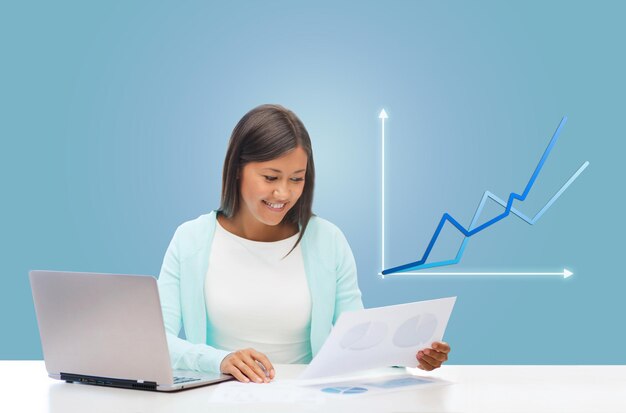 Geschäfts- und Technologiekonzept - asiatische Geschäftsfrau oder Studentin mit Laptop, Dokumenten und Grafik im Büro