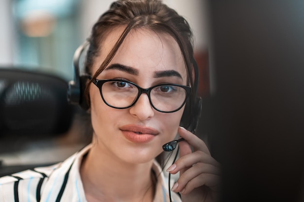 Geschäfts- und Technologiekonzept - Helpline-Betreiberin mit Kopfhörern in einem Callcenter.Geschäftsfrau mit Headsets, die in einem Callcenter arbeitet. Hochwertiges Foto