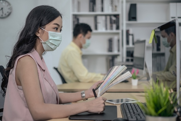 Foto geschäftsarbeit im büro mit gesichtsmaske soziale distanz quarantäne während covid19 beeinflussen