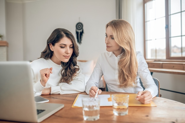 Geschäftsbedingungen. Zwei Frauen sitzen am Tisch und diskutieren über die Vertragsbedingungen