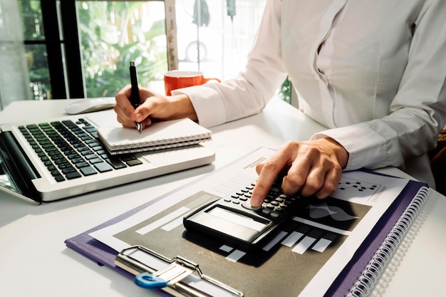 Geschäftsbuchhaltungskonzept Geschäftsmann mit Taschenrechner mit Computer-Laptop-Budget und Kreditpapier im Büro