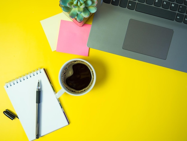 Geschäftsbüro-Schreibtischkonzeptideen Draufsicht mit Laptopkaffee und -aufklebern auf gelbem Hintergrundkopienraum