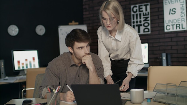 Geschäftschefin kritisiert die Arbeit junger Fachkräfte in einem dunklen Büro. Schlechte Arbeit