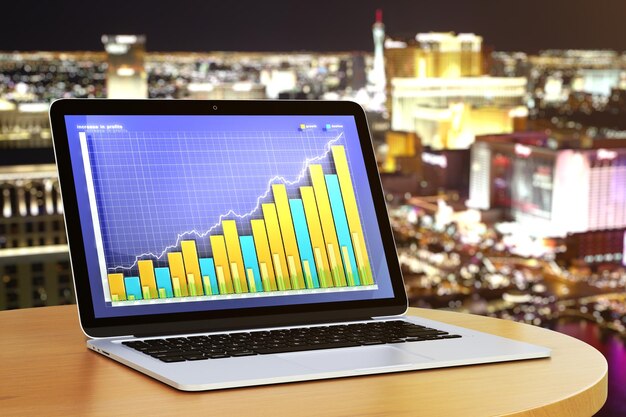 Geschäftsdiagramm auf Laptop-Desktop auf rundem Holztisch bei Nachtstadthintergrund