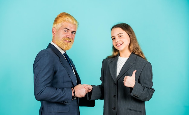 Geschäftserfolg Familienunternehmen Partnerschaft Teamarbeit von Tochter und Vater Geschäftstreffen modernes Büroleben Geschäftsmann gefärbtes blondes Haar kleines Mädchen in übergroßer Anzugjacke zukünftige Karriere