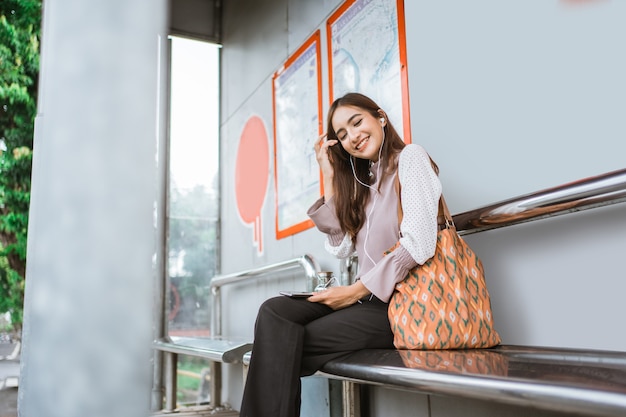 Geschäftsfrau an einer Bushaltestelle, die auf den Bus wartet