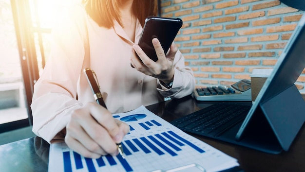 Geschäftsfrau arbeitet mit Laptop-Computer, Tablet und Smartphone im modernen Büro mit virtuellem Symboldiagramm im Modernoffice im Morgenlicht