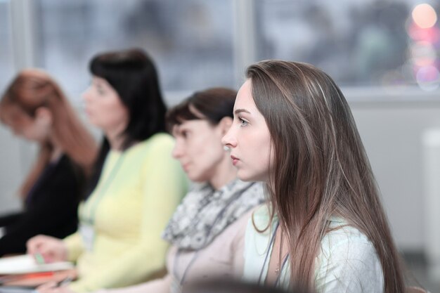 Geschäftsfrau auf unscharfem Hintergrund von Kollegen im Konferenzraum.