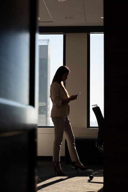 Geschäftsfrau benutzt ein Handy in einem modernen Büro