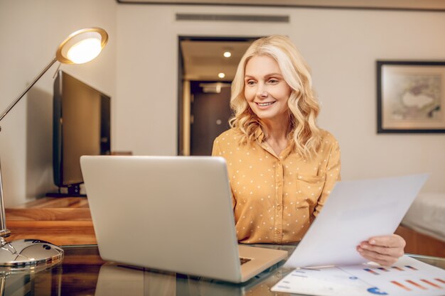 Geschäftsfrau. Blonde stilvolle Geschäftsfrau, die am Tisch arbeitet und beteiligt aussieht looking