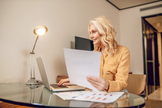 Geschäftsfrau. Blonde stilvolle Geschäftsfrau, die am Tisch arbeitet und beteiligt aussieht looking