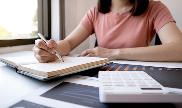 Geschäftsfrau Buchhalter Handnote Analyse der Grafik mit Taschenrechner und Laptop im Home Office