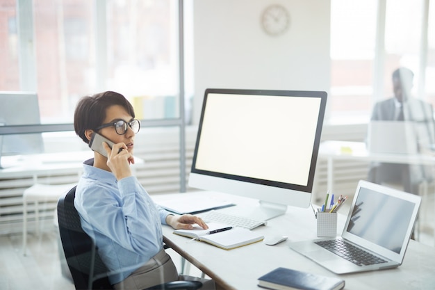 Geschäftsfrau, die am Arbeitsplatz telefonisch spricht