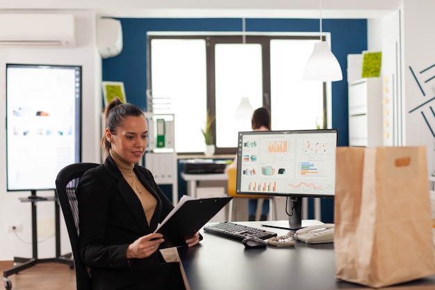 Geschäftsfrau, die am Schreibtisch in der Unternehmenszentrale sitzt und Finanzstatistiken liest