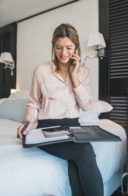 Geschäftsfrau, die am Telefon am Hotelzimmer spricht.